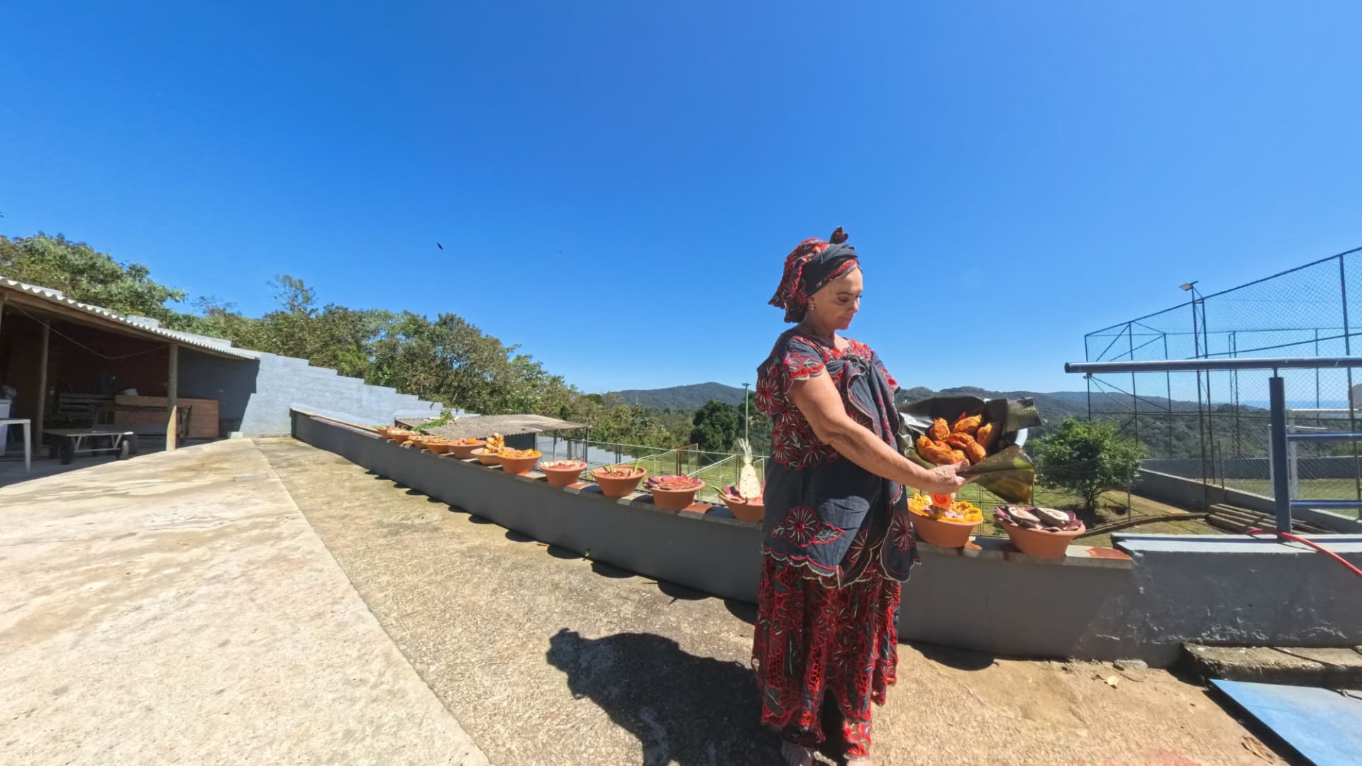 Oferendas dispostas em alguidares de barro ao ar livre, sob o sol
